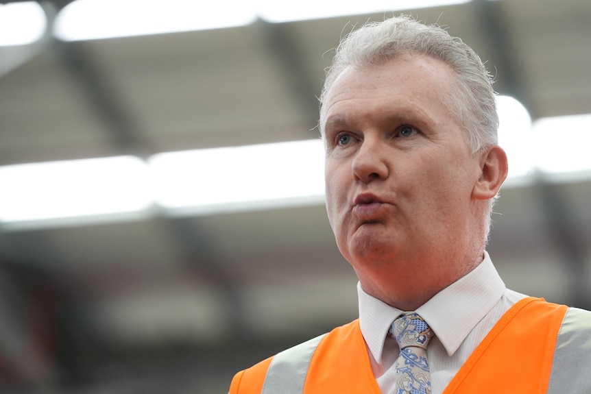 Burke speaks while wearing a high-visibility vest.