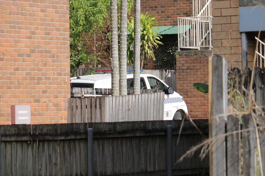 A police car is parked at a brick block of residential units in Annerley