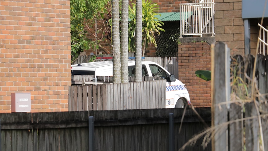 A police car is parked at a brick block of residential units in Annerley