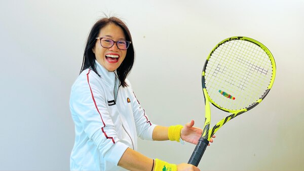 Lisa Leong holding a tennis rack against white background