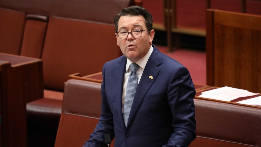 Dean Smith stands at his desk in the Senate, gesturing while speaking into a microphone