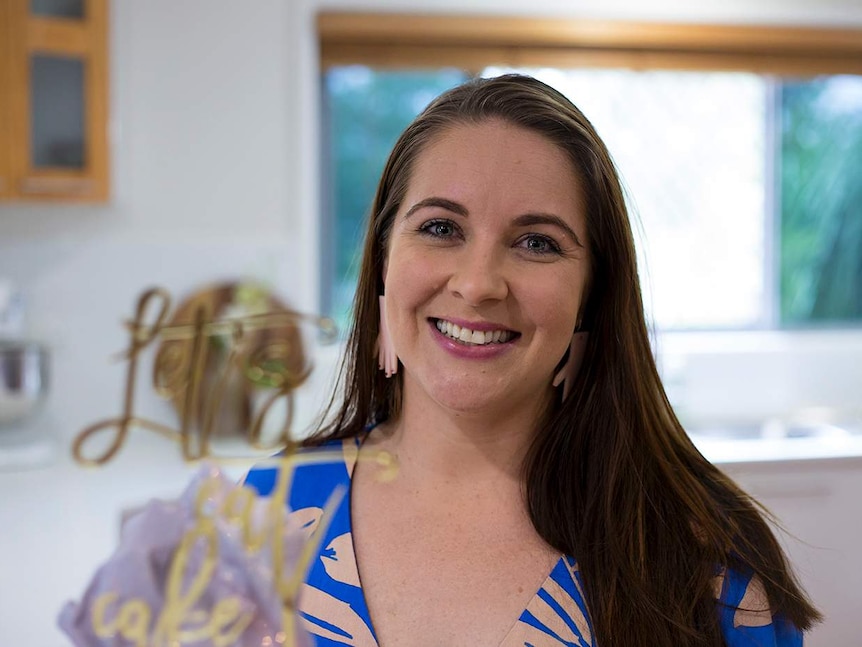 A woman smiles at the camera with 'let's eat in cake' in the foreground