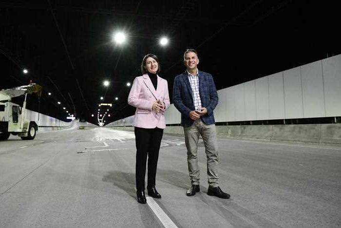 Gladys Berejiklian in a pink jacket in a motorway tunnel with Andrew Constance