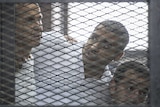 Peter Greste and his colleagues listen to the verdict inside the defendants cage