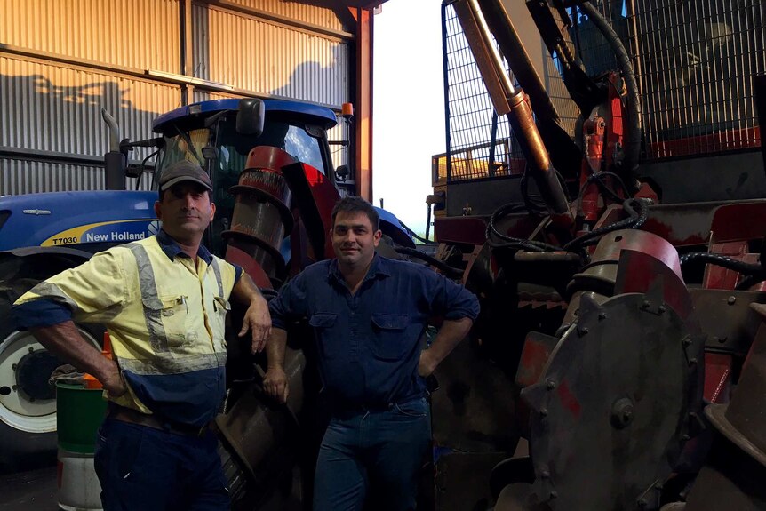 Cane farmer Jeff Grech and harvest contractor Travis Andrew stand with a harvester.