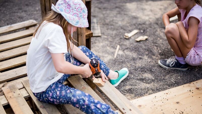 A child uses a power drill on a piece of wood