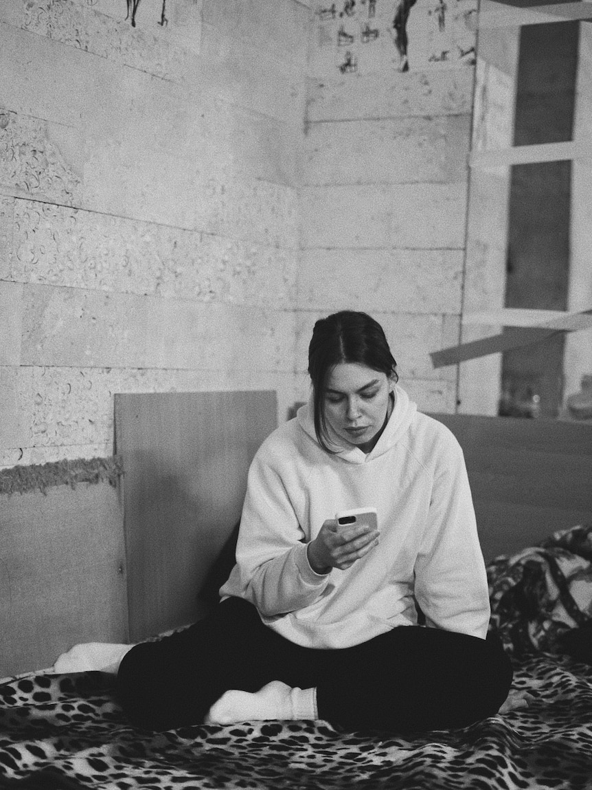 A black and white image of a woman looking at her phone. 