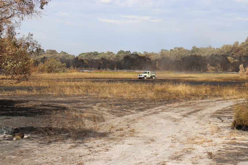 A fire truck in the distanced drives across scorched earth