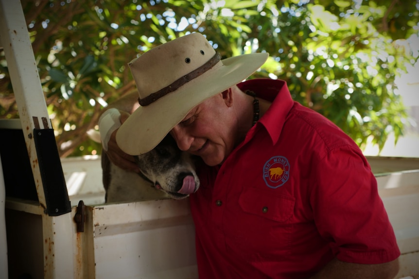 Alan Gray stands next to his ute and pats his dog, who sits in the ute's tray.