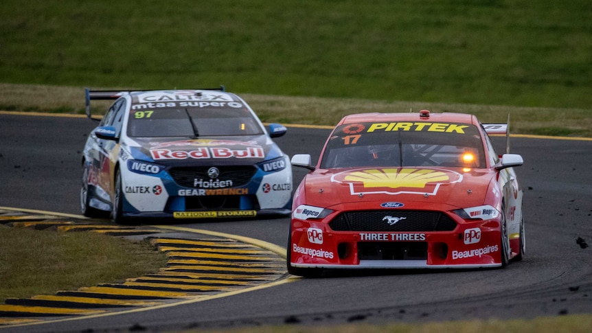 A red Ford Mustang with a number 17 in the window leads a white and blue Holden Commodore with Red Bull written on it