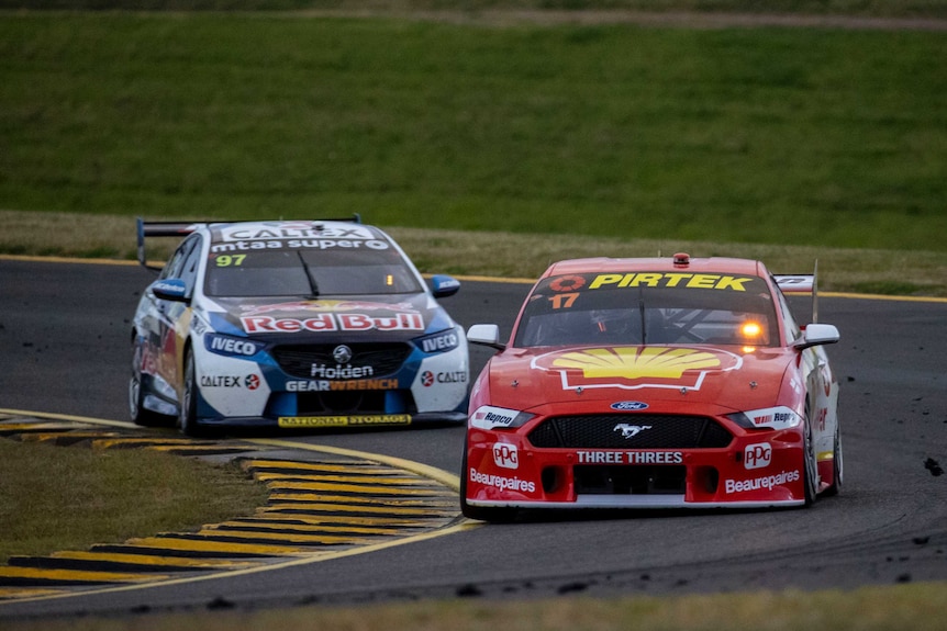 A red Ford Mustang with a number 17 in the window leads a white and blue Holden Commodore with Red Bull written on it