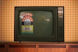 An illustration shows an old TV with an energy rating sticker sitting on a shelf in a living room.