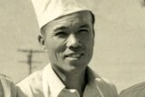 A black and white photo of a Japanese man, he is smiling