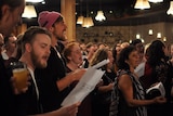 Singers with lyric sheets and beers in their hands.