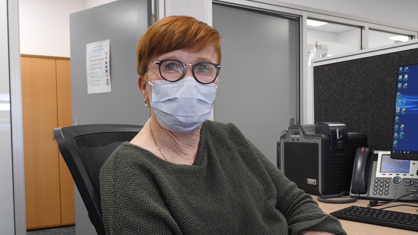 Kathy Seward sitting at a desk with a mask on.
