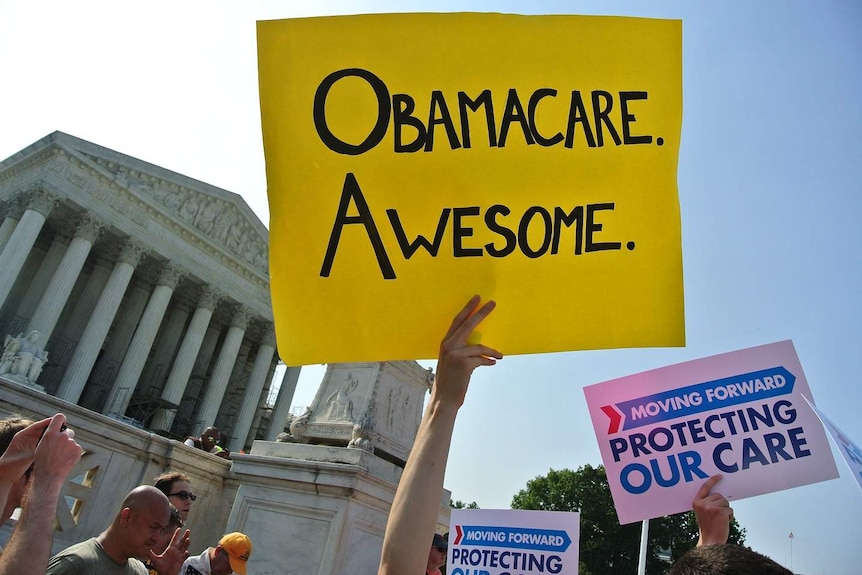 A bright yellow cardboard sign reads 'Obamacare. Awesome.' outside the US Supreme Court.