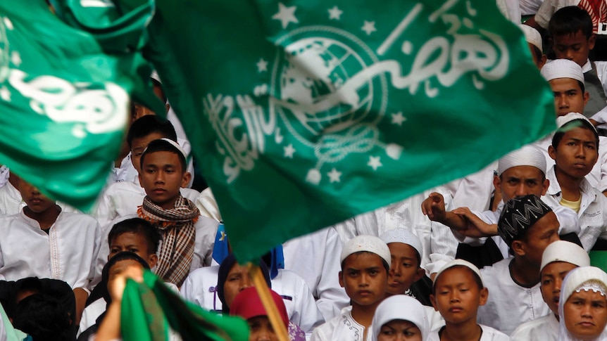 a group of people bring a big flag with arabic letters