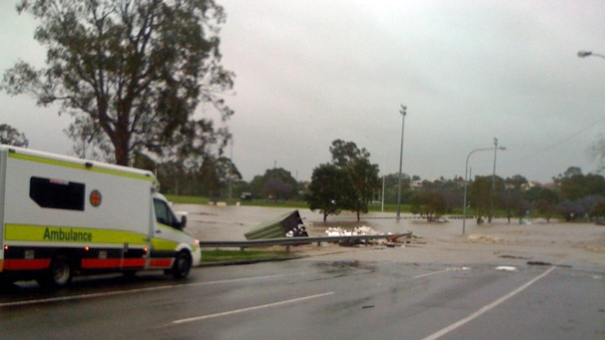 An ambulance drives along a flooded road in Wooloowin, Brisbane.