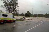 An ambulance drives along a flooded road in Wooloowin, Brisbane.