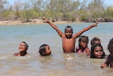 Indigenous kids playing in blue water on Mornington Island
