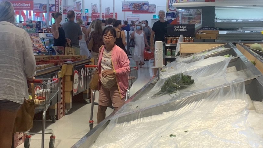 Shopper queue in a supermarket that's running low on supplies.