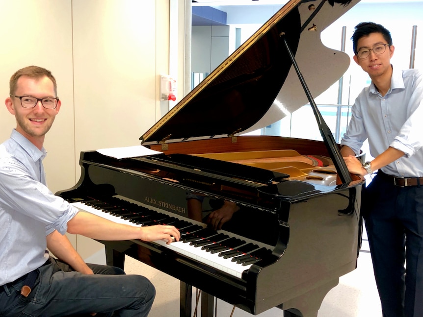 Two young doctors at a grand piano in a hospital foyer