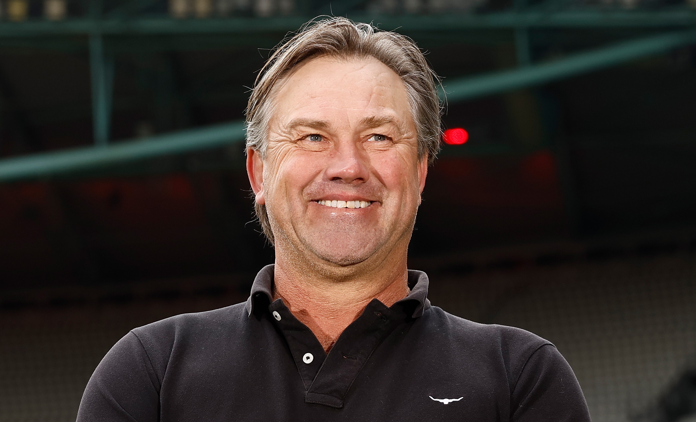 A man wearing a black shirt smiles.