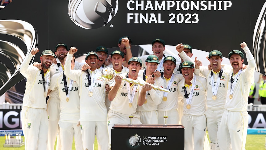 The Australian team gather around Pat Cummins, who holds the mace trophy awarded to the World Test Championship winners