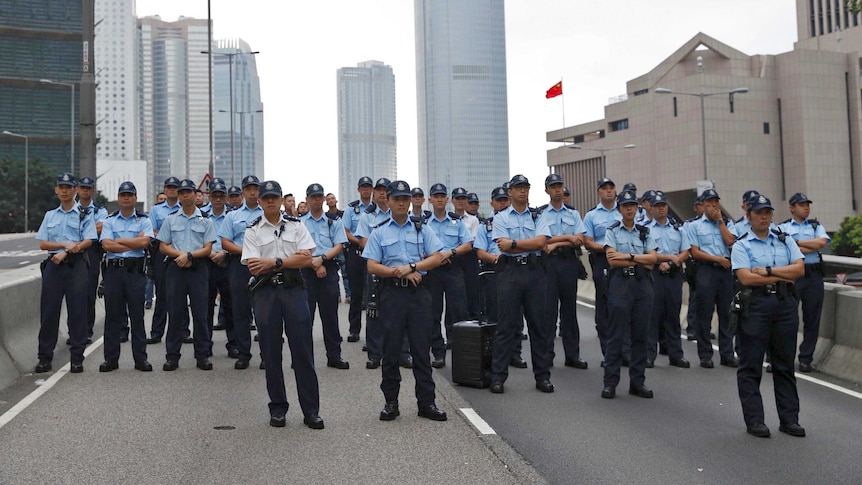 A large group pf policemen block off a road