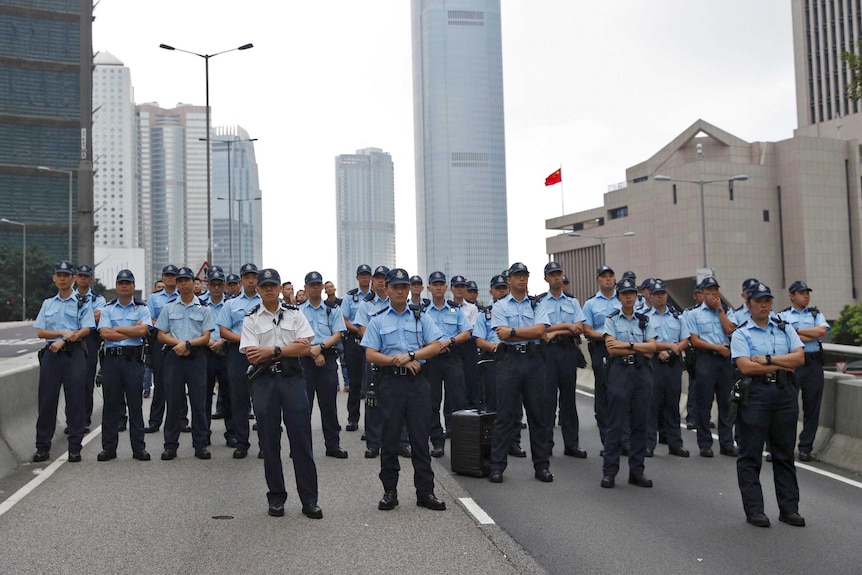 A large group pf policemen block off a road