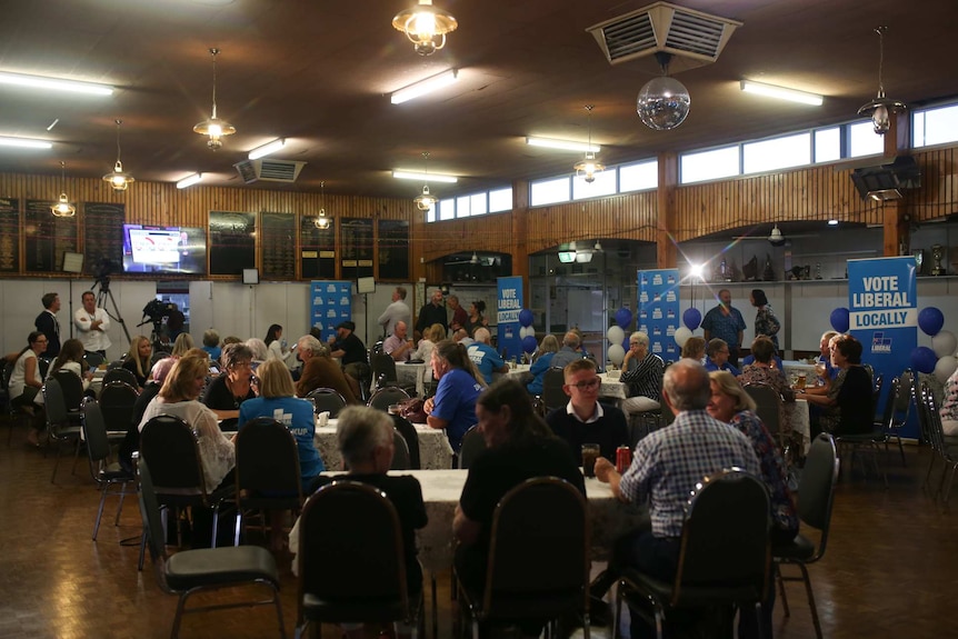 Liberal supporters seated at tables looking glum.