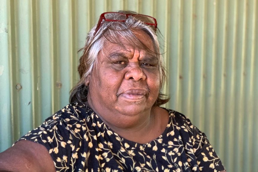 Rosita Stumpagee sits in front of a corrugated iron building.