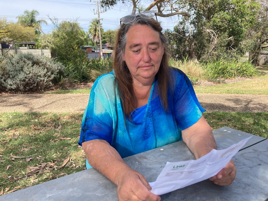 A woman looking at a piece of paper in her backyard