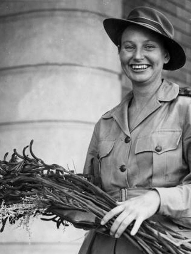 Black and white photo of a young woman, a nurse with a warm smile holding a bunch of flowers 