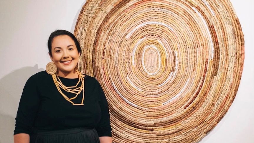 artist Jessika Spencer in front of her woven artwork on the wall