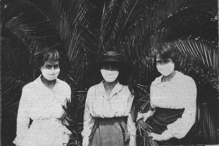 Three typists stand in the Sydney Botanical gardens wearing masks during the 1919 influenza pandemic.