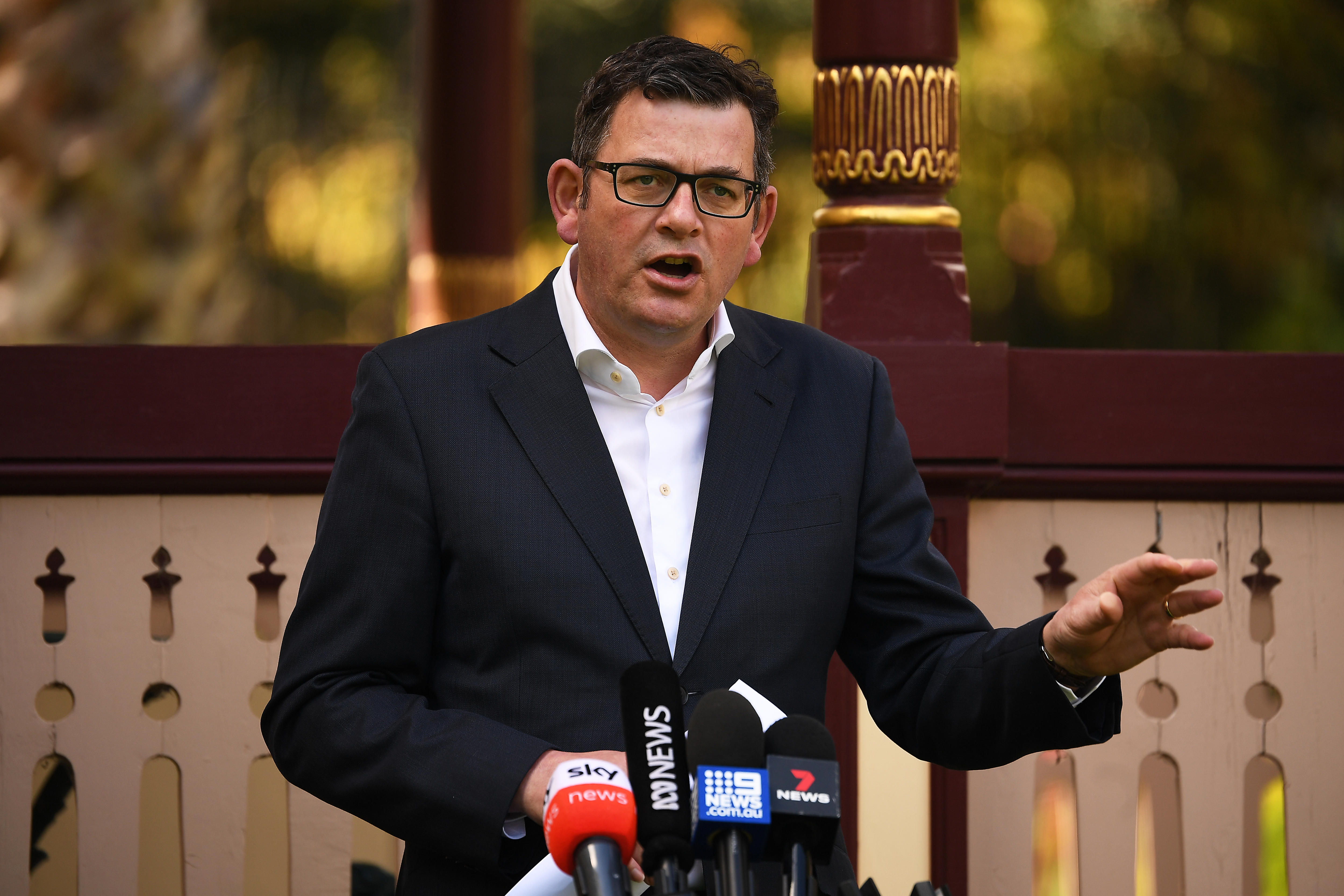 Dan Andrews gestures while speaking to the media