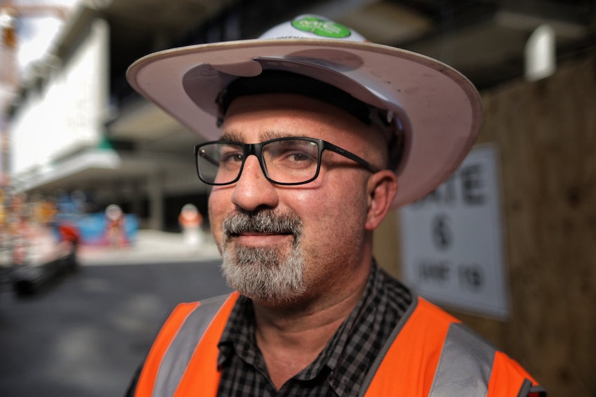 A close-up shot of a man in high-vis and a construction hat.