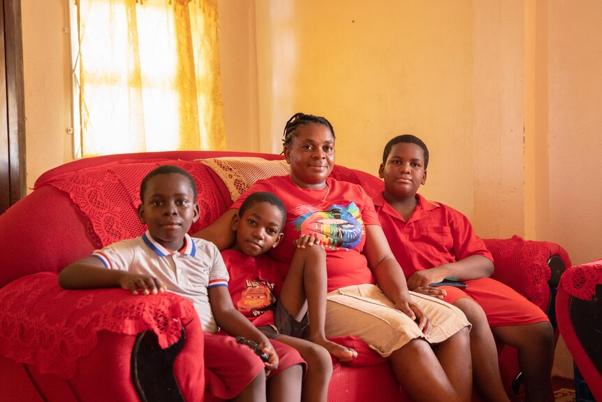 Shawndel Hilken sit with her family at home on a red couch