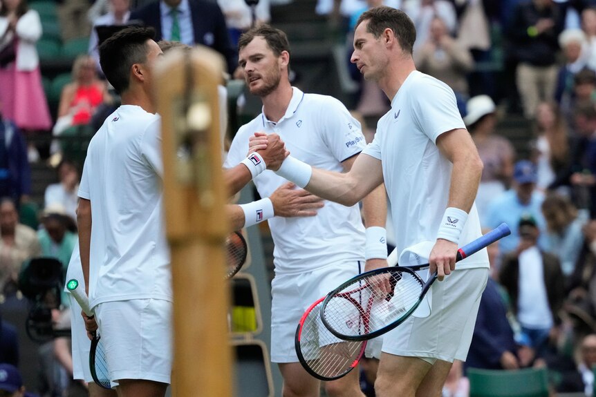 British tennis player Andy Murray and his brother Jamie shake hands with two Australian players at the net.