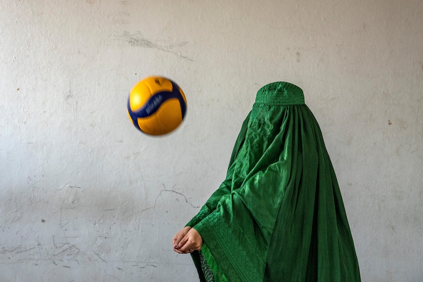 An Afghan volleyball player poses for a photo wearing a burqa.
