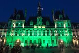 Paris City Hall is lit up green at night time.