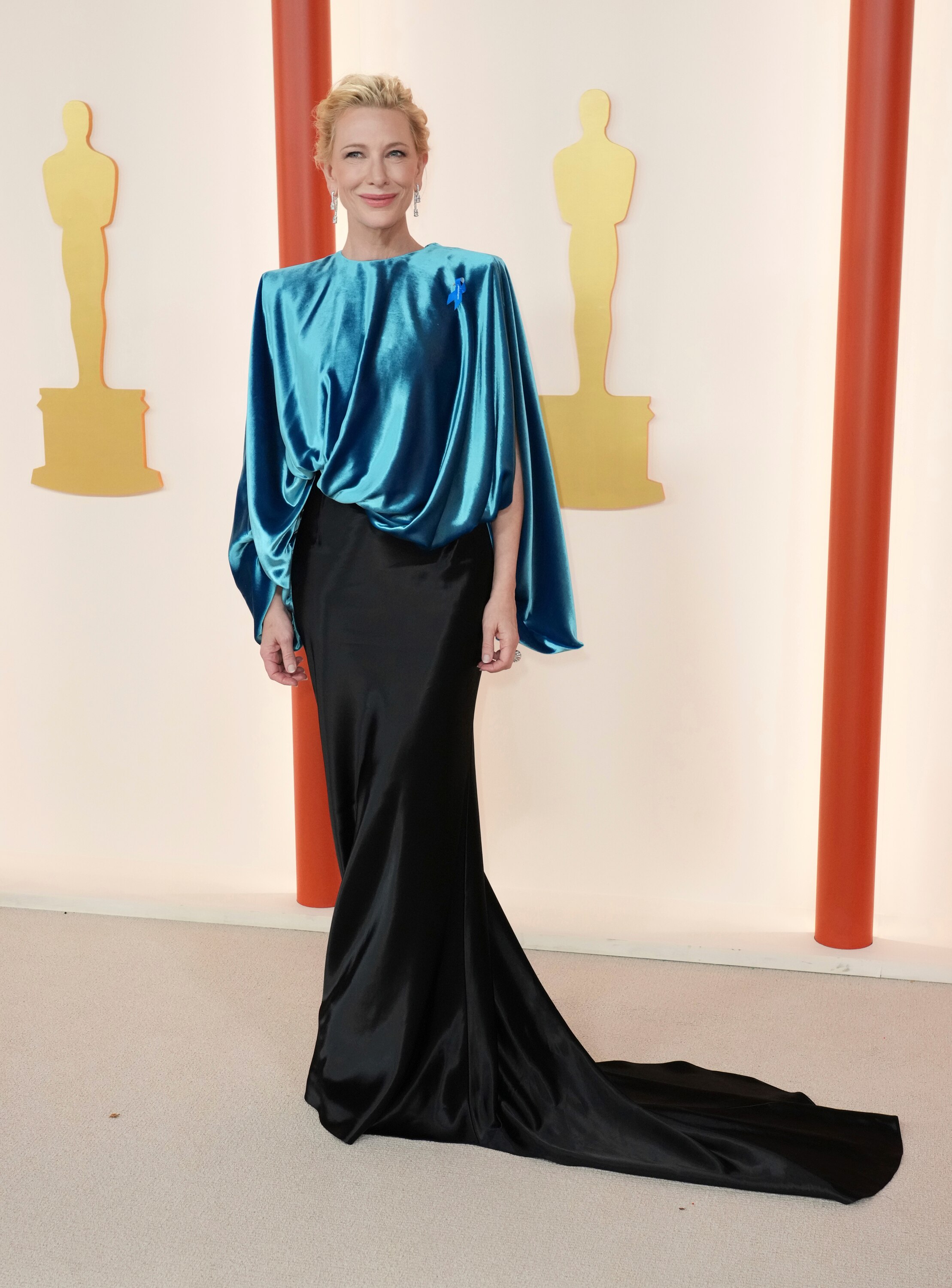 Cate Blanchett wearing a long-sleeved silk blue top with a slim-fitting black skirt with a long train