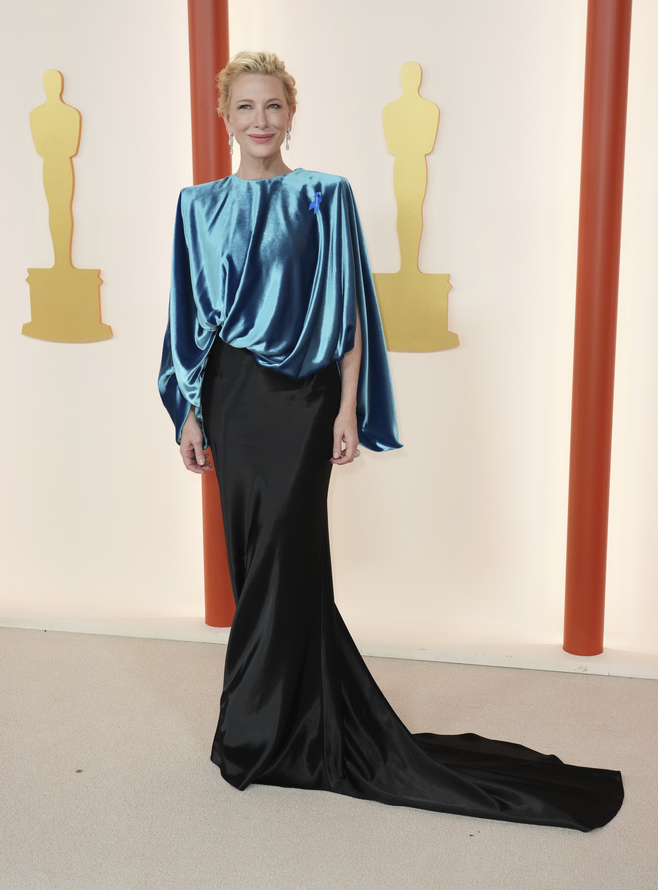 Cate Blanchett wearing a long-sleeved silk blue top with a slim-fitting black skirt with a long train
