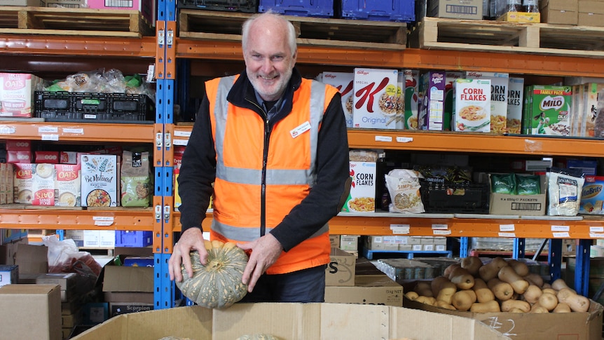 Albury Wodonga Regional FoodShare Manager Peter Matthews stands in front of a large bin of donated pumpkins