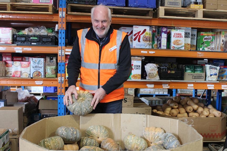 Albury Wodonga Regional FoodShare Manager Peter Matthews stands in front of a large bin of donated pumpkins