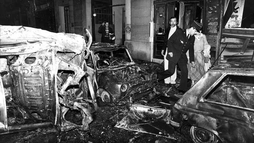 a black and white image of wreckage to vehicles caused on a street by a bombing in Paris
