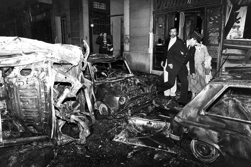 a black and white image of wreckage to vehicles caused on a street by a bombing in Paris