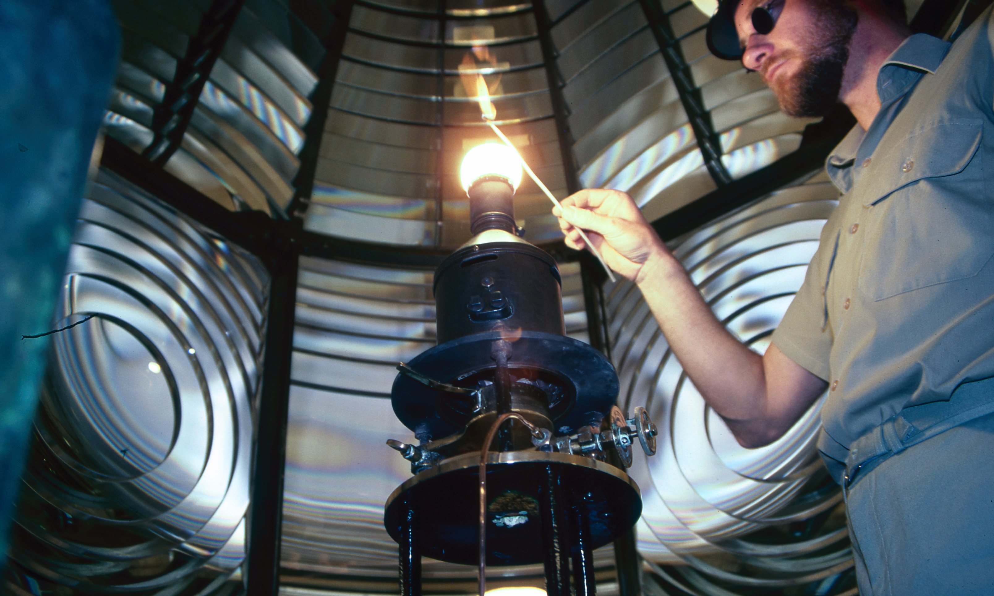 Un hombre enciende la llama en lo alto de un faro.