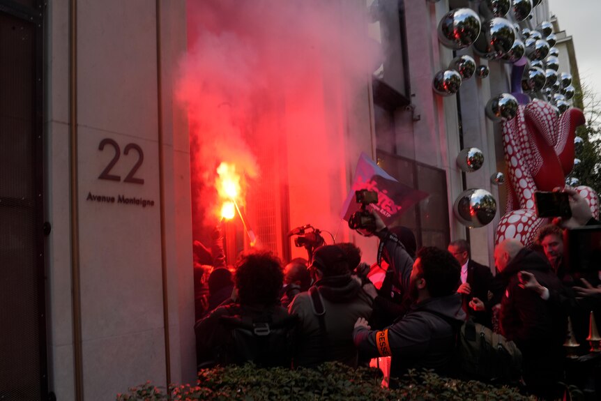 People streaming into a building holding red flares 